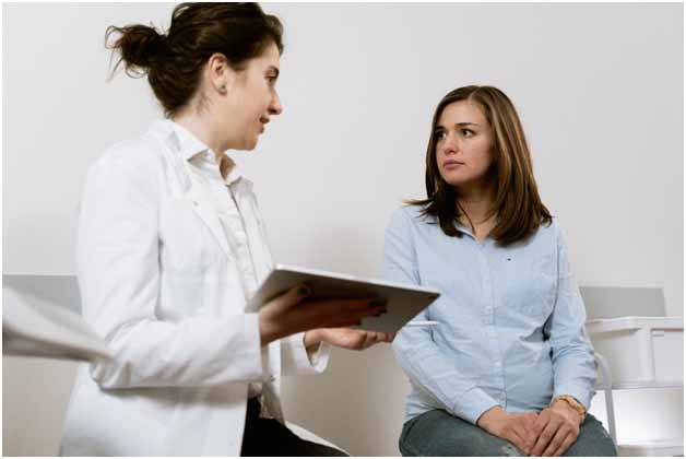 Woman in blue shirt consulting a doctor